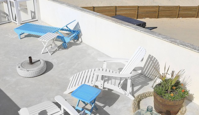 House situated by the sea, on a long white sandy beach.